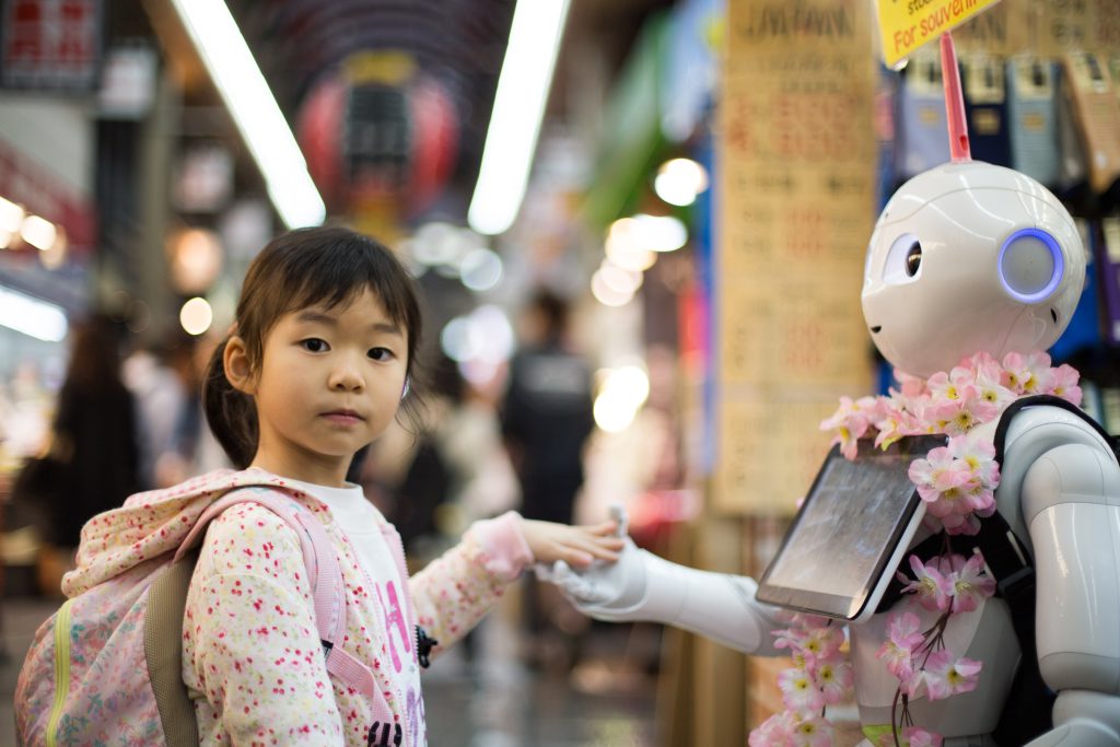 young girl touches hand of an assistant robot